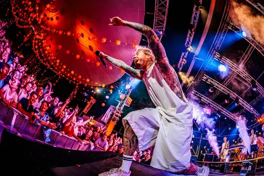 Zanger van The Dirty Daddies leunt over het publiek op een festival